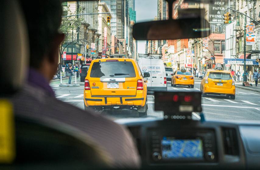A view from the interior of a taxi looks out to a busy street in New York City.